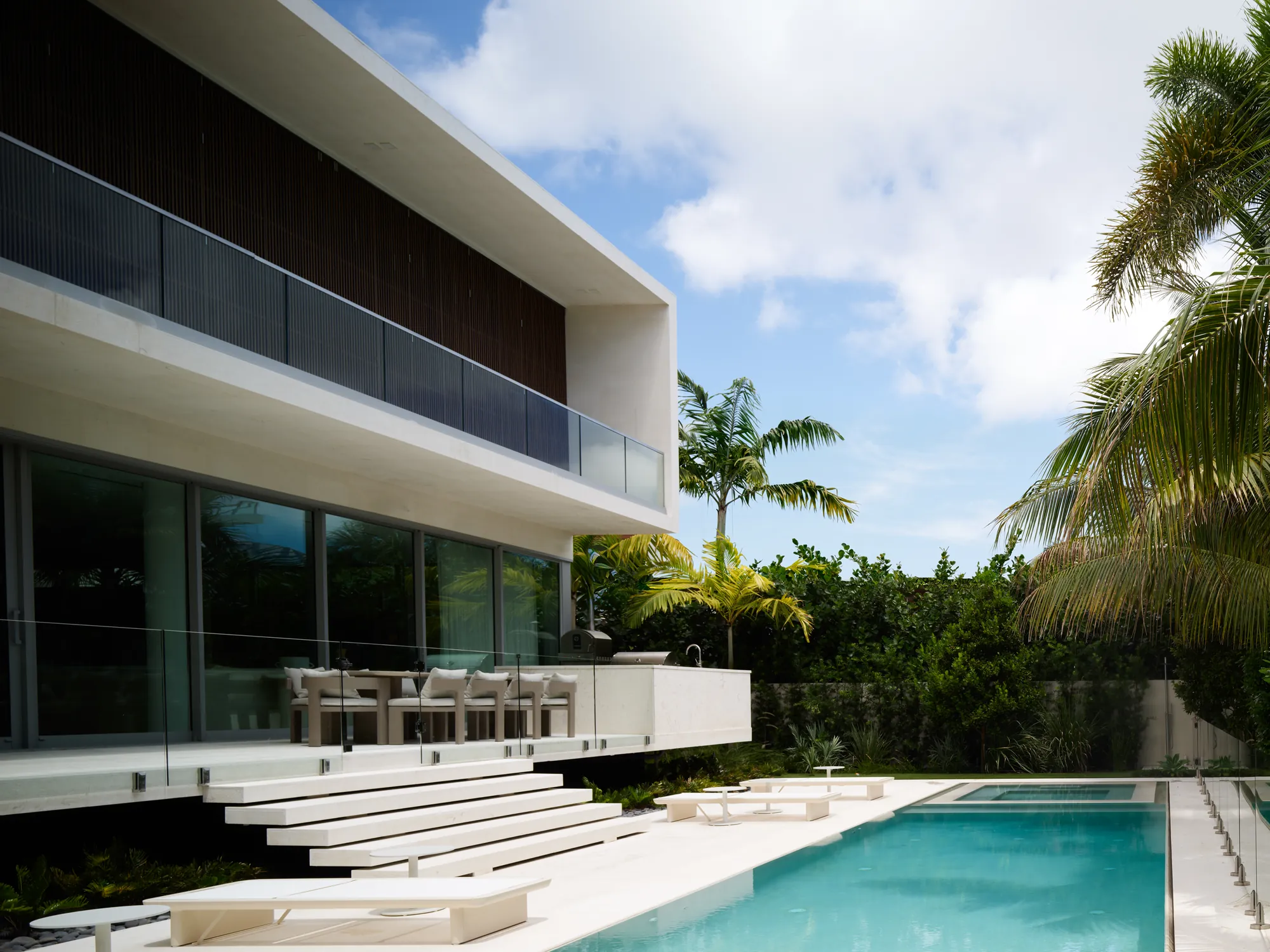 The finished pool terrace at the Broadview Residence in Miami, a lap pool and white stone deck sitting under the home's cantilevered upper level, the same terrace shown in Luxom's stage by stage build timelapse