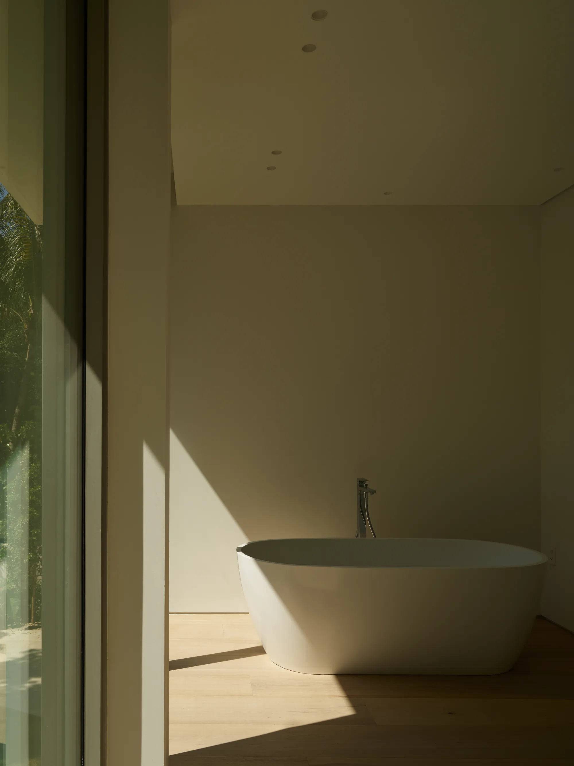 Bathroom with a freestanding tub and natural-stone surfaces in the Ingraham residence by LUXOM, Miami