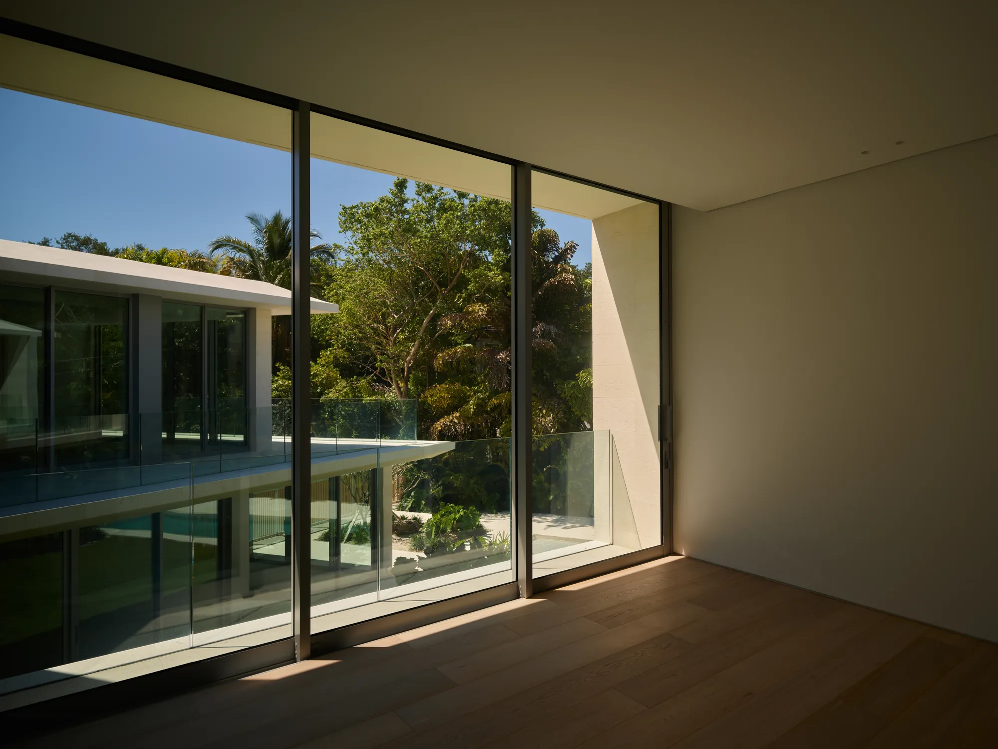 Kitchen with a stone island open to the garden in the Ingraham residence by LUXOM, Miami
