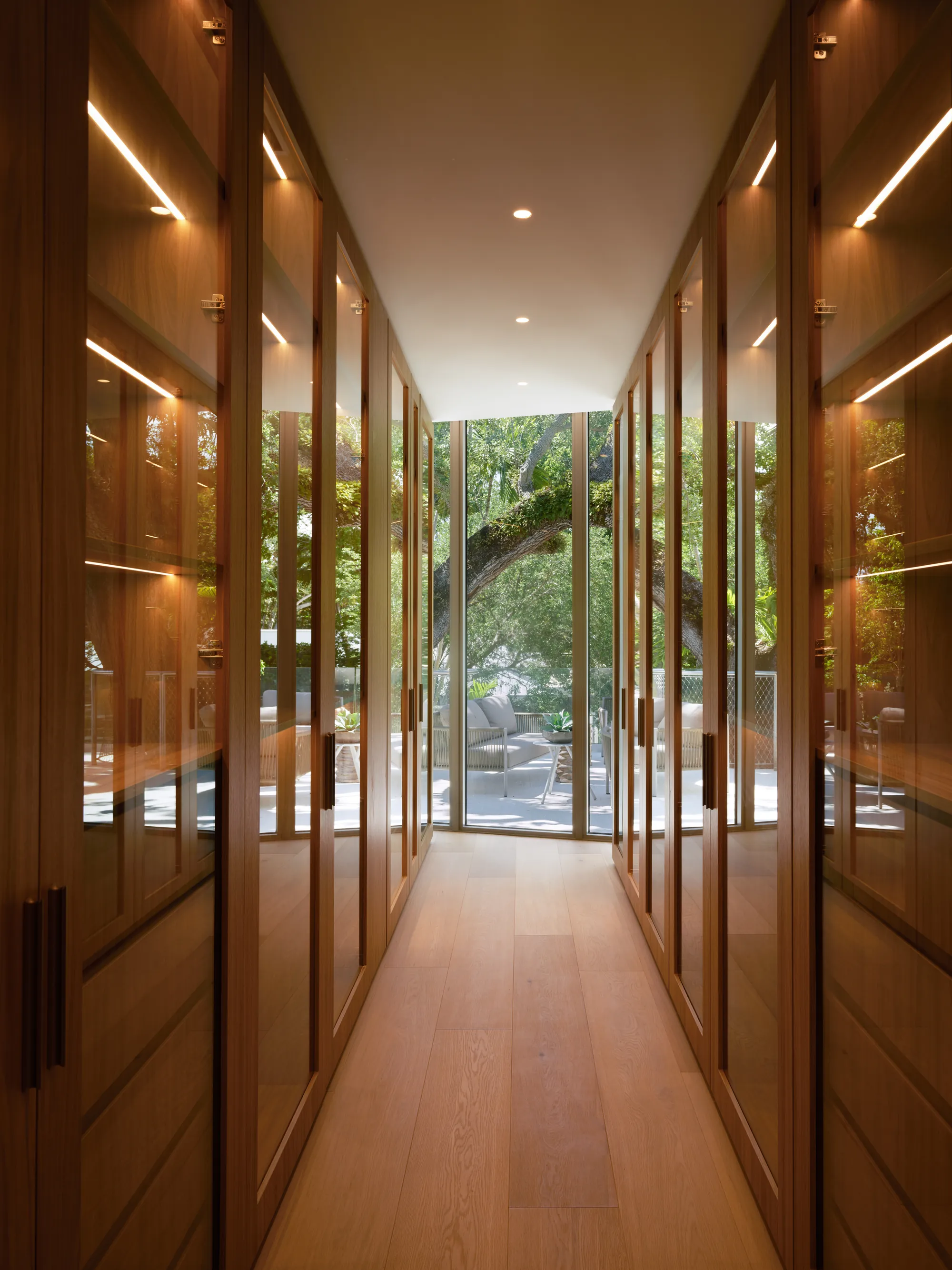 Fluted white-oak wall panelling lining a gallery corridor in the Onaway residence by LUXOM
